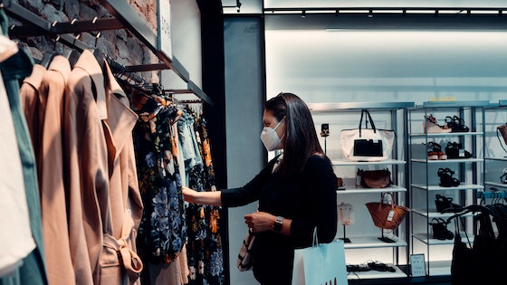 Woman in protective mask shopping at retail clothes store