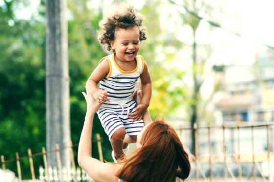 Young woman holding smiling child up in air