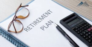 Glasses, pen, and calculator set on top of retirement plan