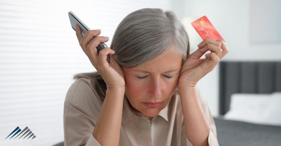 A senior woman frustrated with her phone and credit card