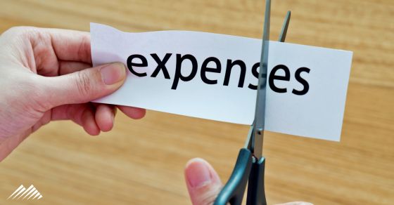 scissors cutting paper with the word expenses on it