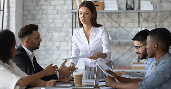 An employee distributes papers to her coworkers