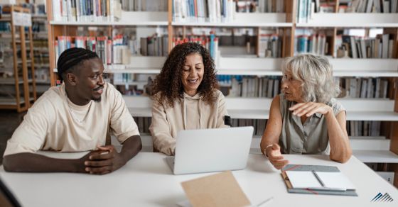 Three people at a desk smiling and talking
