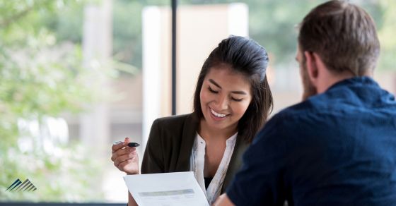 A woman at a desk helps a man with a bank loan