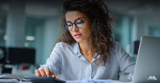 A woman using a calculator and computer