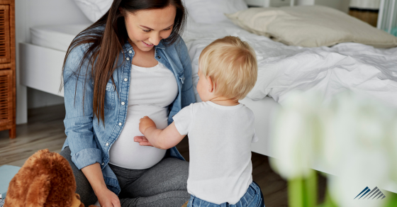 A toddler touching his mom's pregnant belly