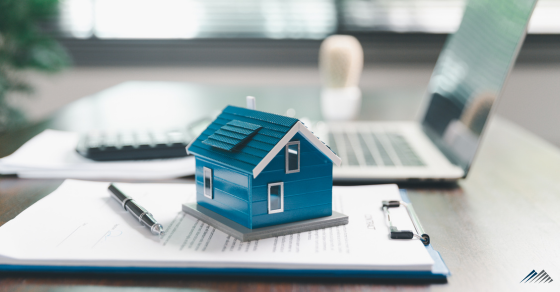 A replica of a home sits on paperwork
