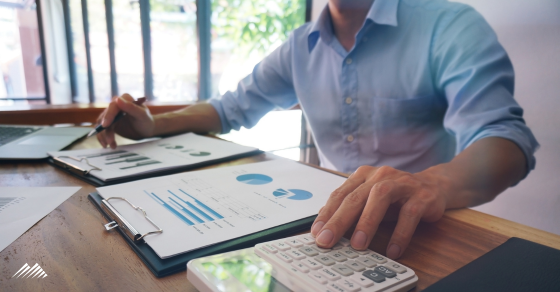 A man at a computer with paperwork and a calculator