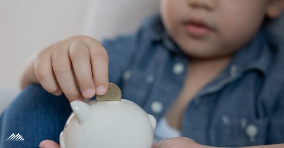 A young child puts coins into a piggy bank