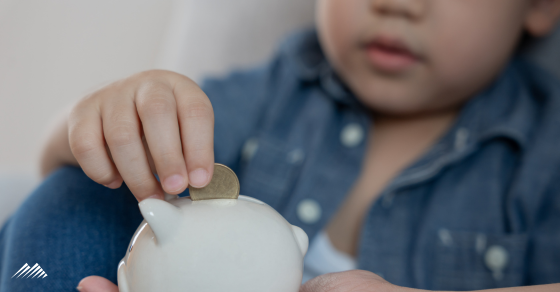 A young child puts coins into a piggy bank