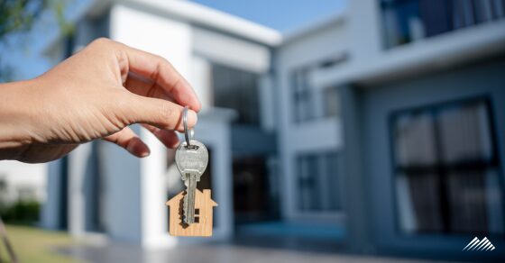 Hand holding keys in front of a home